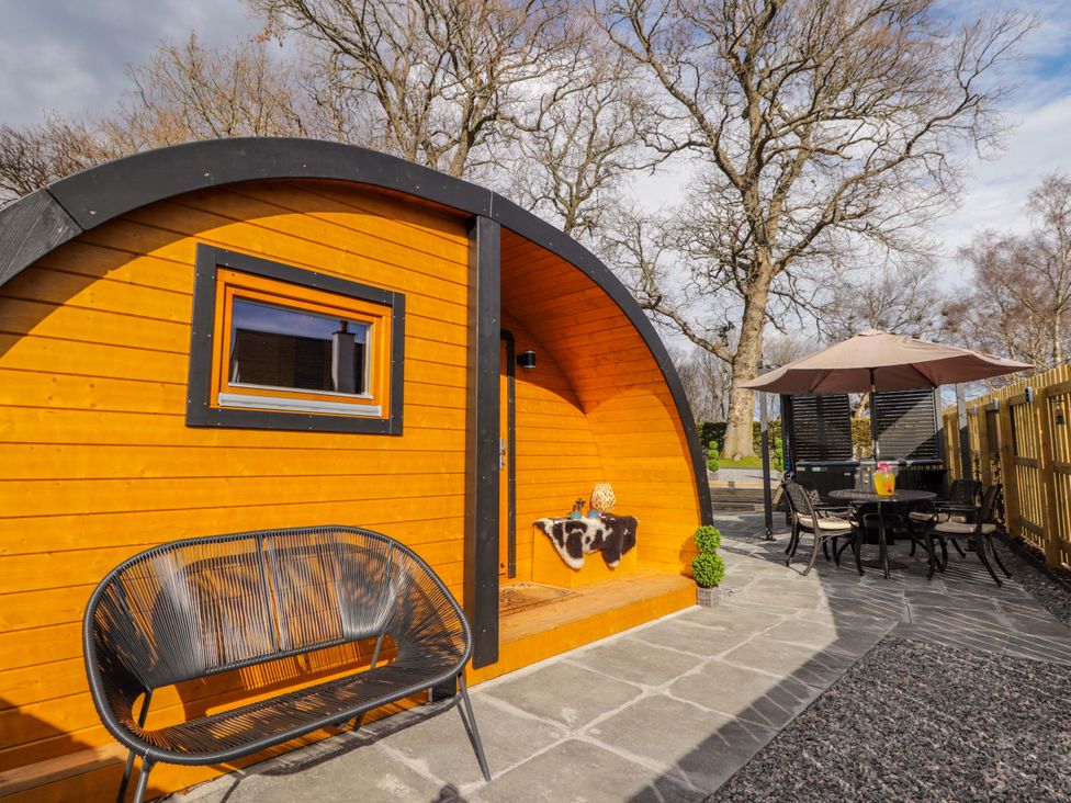 An outdoor space with a wooden cabin and seating at Little Oaks in Poyntzfield near Cromarty