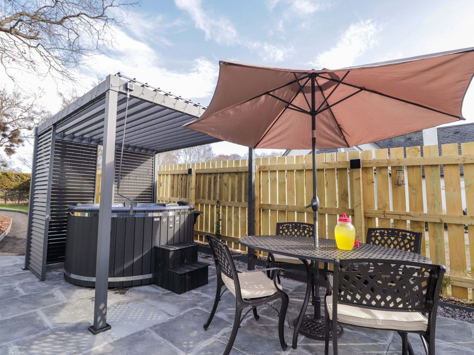 An outdoor area with a hot tub and dining set at Little Oaks in Poyntzfield near Cromarty