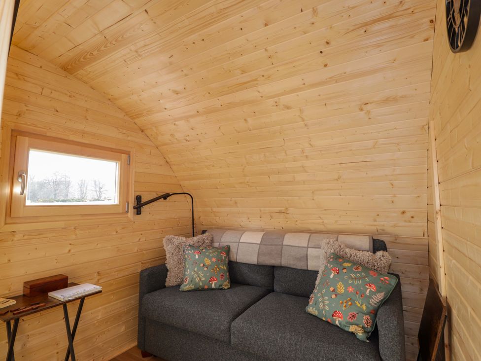 A snug with a sofa and cushions at Little Oaks in Poyntzfield near Cromarty
