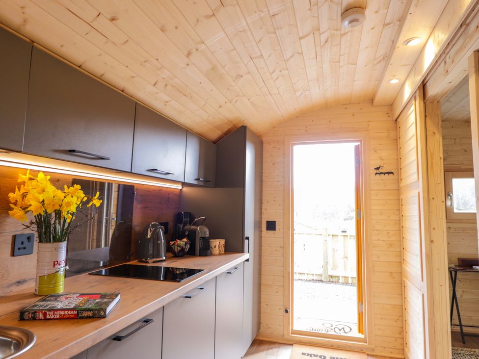 A kitchen with cabinets, a countertop, and a door at Little Oaks in Poyntzfield near Cromarty