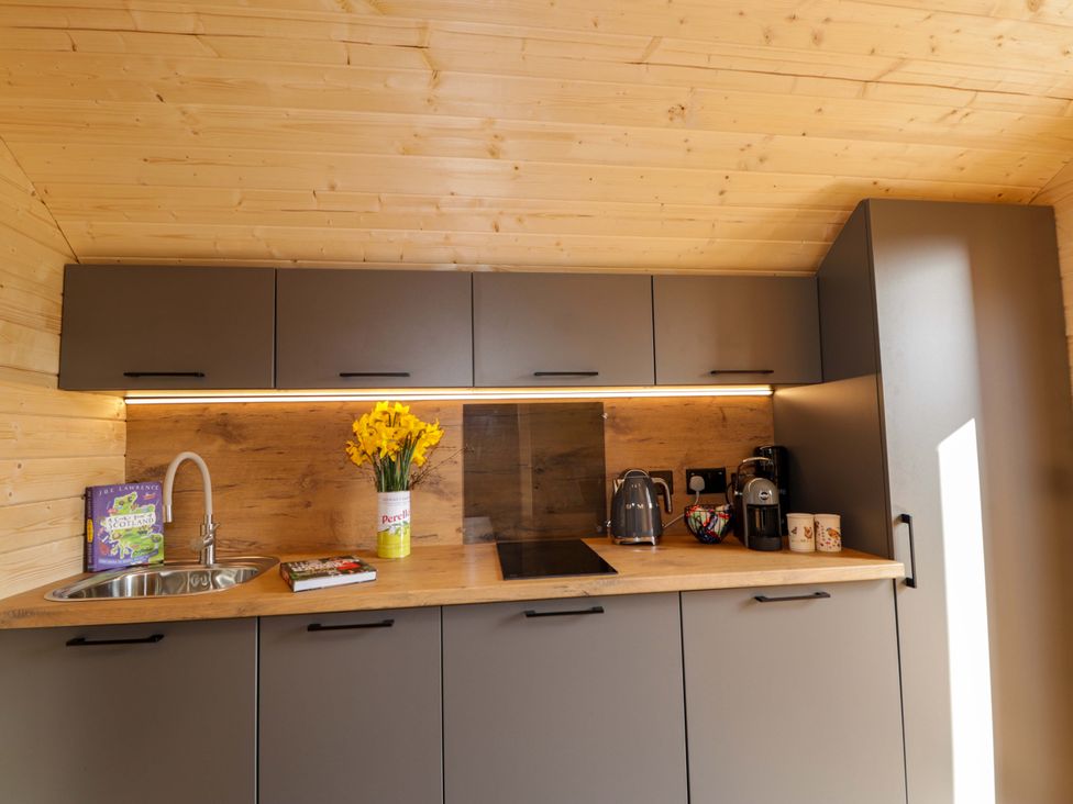 A kitchen with a sink, cabinets, and appliances at Little Oaks in Poyntzfield near Cromarty