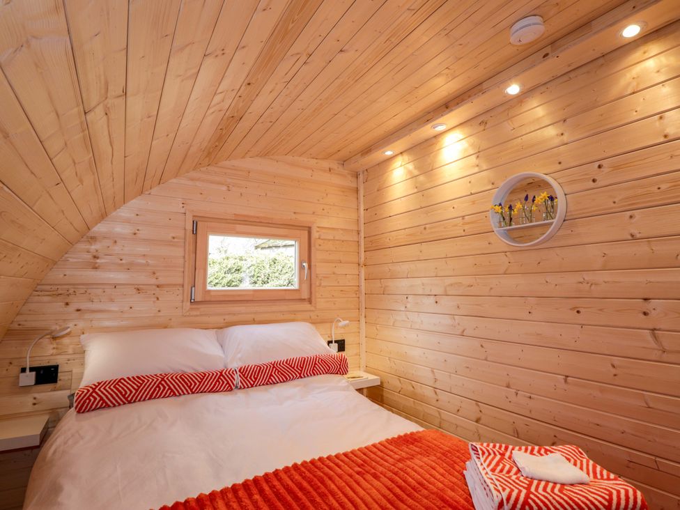 A bedroom with a bed and small window at Little Oaks in Poyntzfield near Cromarty