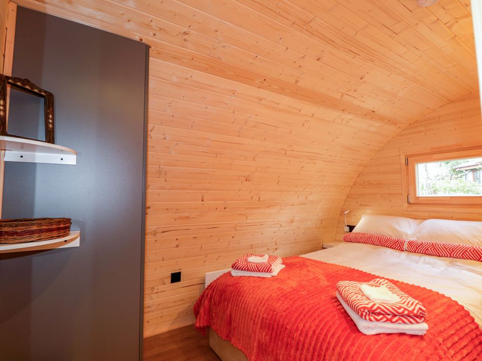 A bedroom with a bed and shelf at Little Oaks in Poyntzfield near Cromarty
