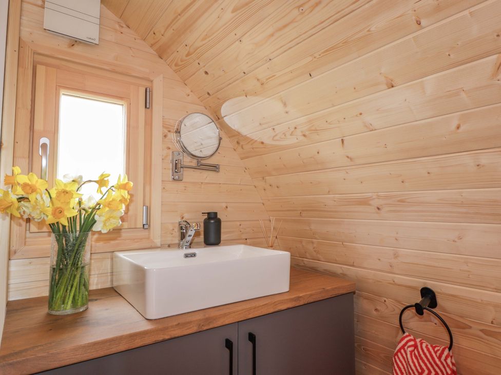 A bathroom with a sink and flowers in a vase at Little Oaks in Poyntzfield near Cromarty