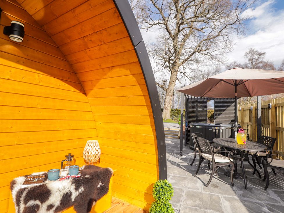 An outdoor seating area with a hot tub and table at Little Oaks Poyntzfield near Cromarty