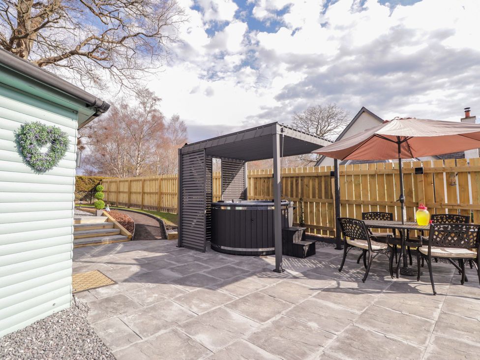 A garden with a hot tub and outdoor seating at Little Oaks in Poyntzfield near Cromarty