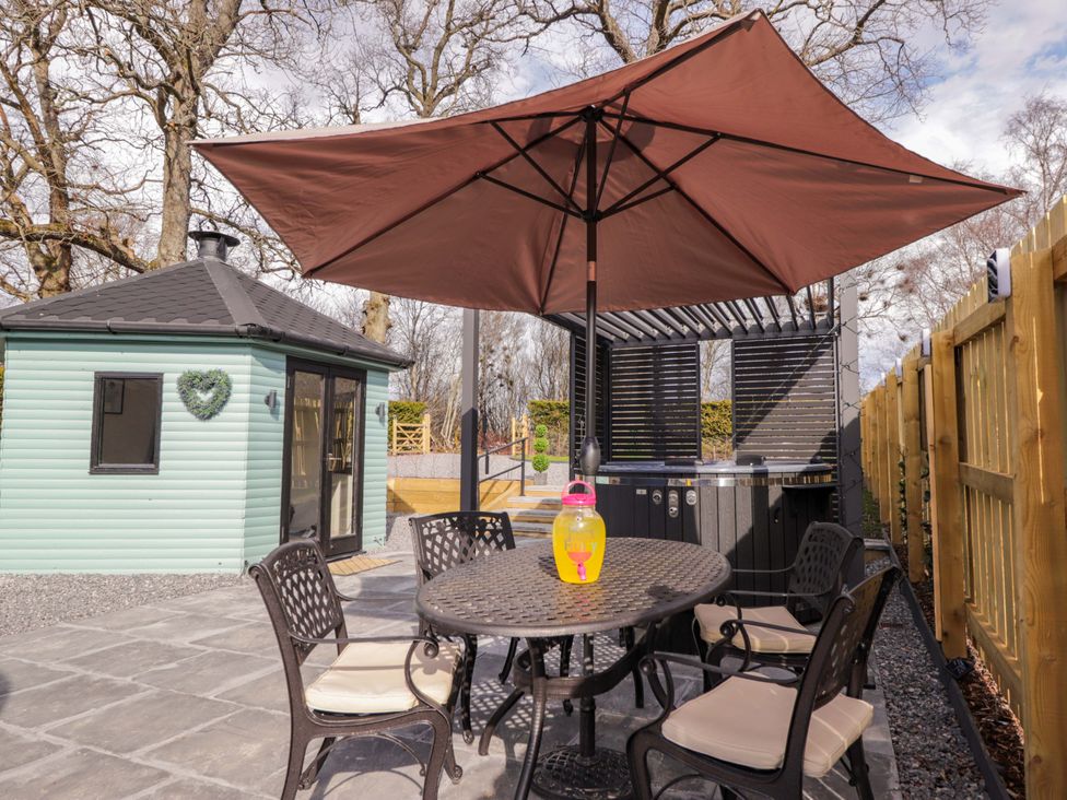 An outdoor area with a table and chairs near a hot tub at Little Oaks in Poyntzfield near Cromarty
