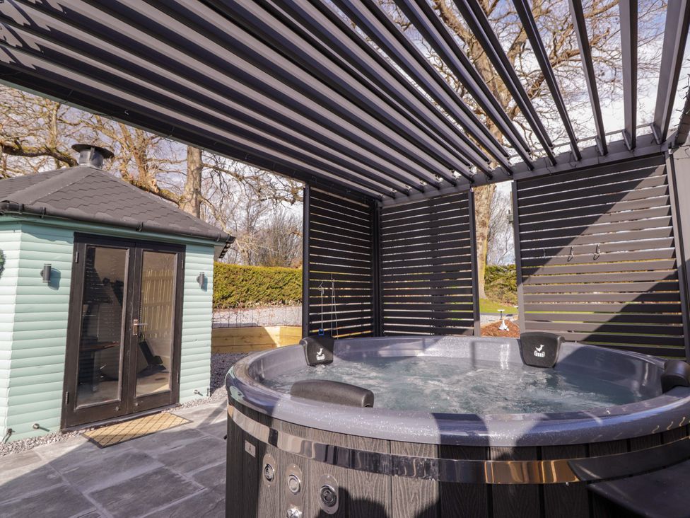 A hot tub under a slatted roof with an outdoor building at Little Oaks Poyntzfield near Cromarty