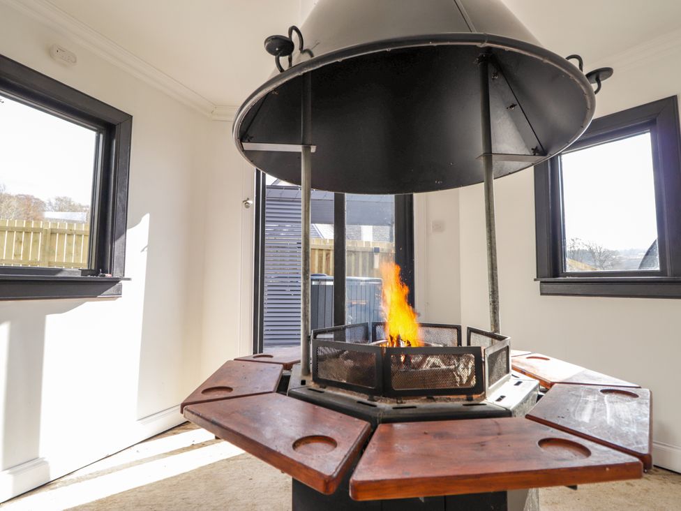 A fire pit with a wooden table around it at Little Oaks in Poyntzfield near Cromarty