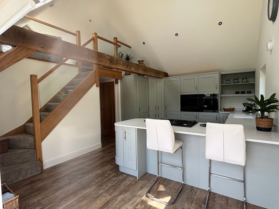 A kitchen with a staircase and bar stools at Ash Tree Lodge in Norwich