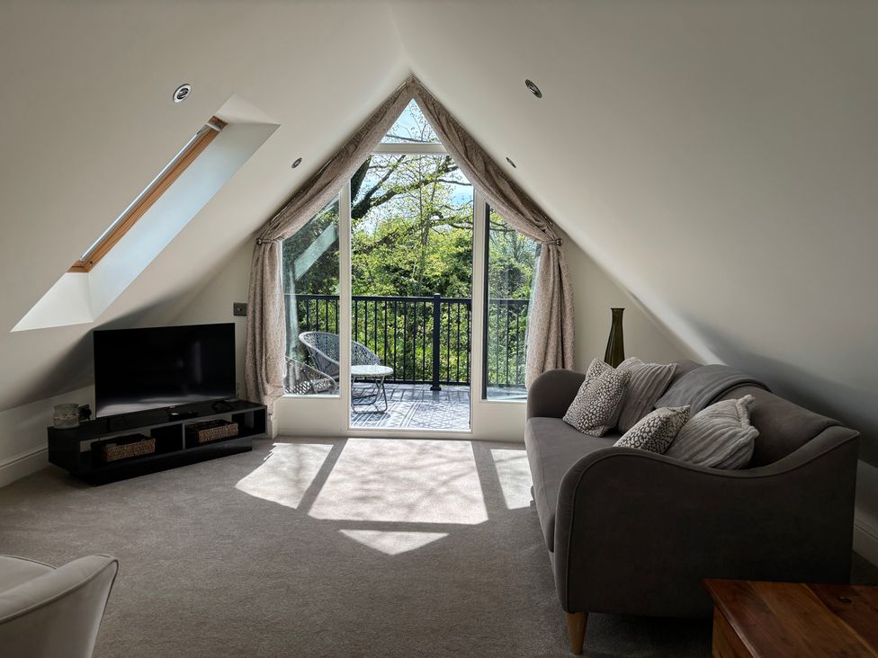 A living room with a television and a balcony at Ash Tree Lodge in Norwich
