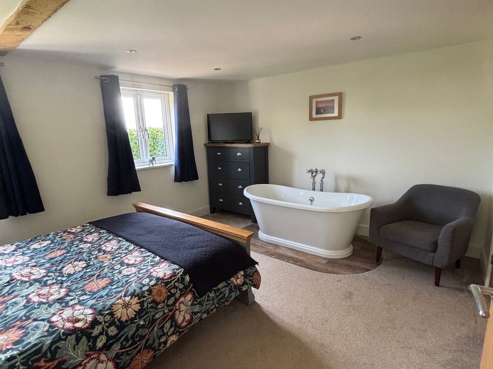 A bedroom with a bathtub and dresser at Ash Tree Lodge in Norwich