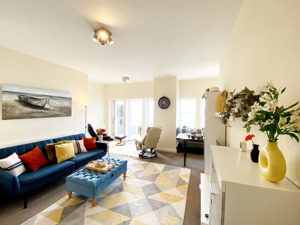 A living room with a blue sofa, coffee table, and armchair at Number 1 Marina Court in Torquay