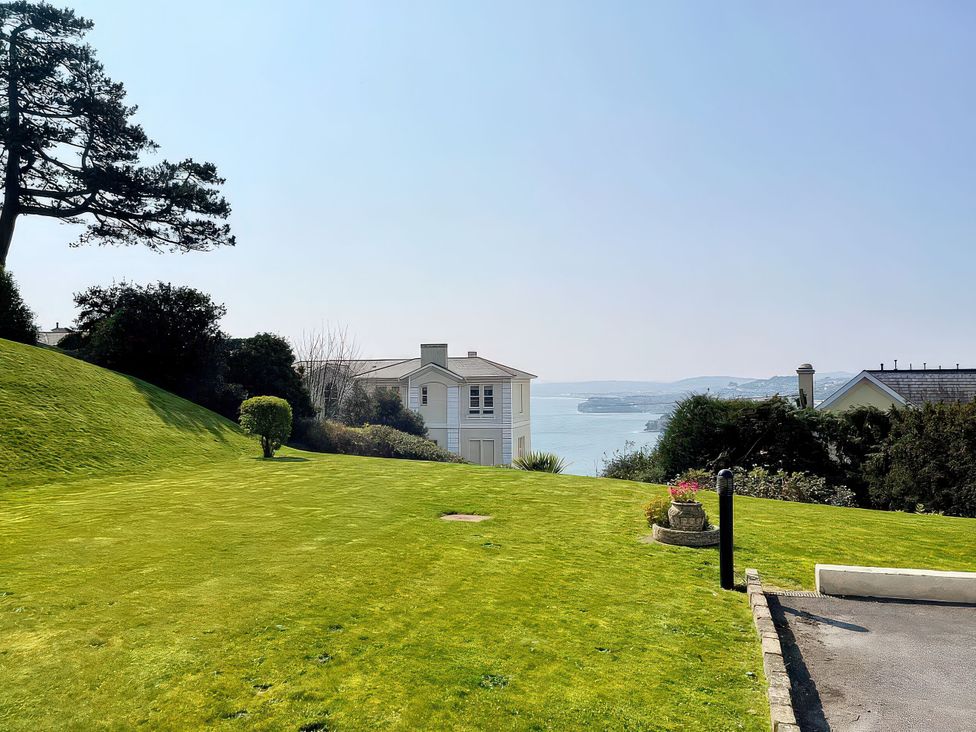 A lawn with a house and water view at Number 2 Ellington Court Apartment Torquay