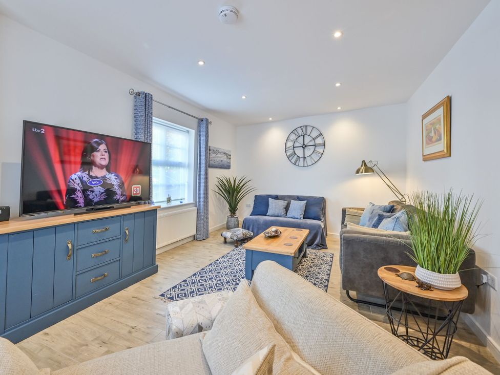A living room with a television, sofa, and coffee table at Number 2 Ellington Court Apartment in Torquay