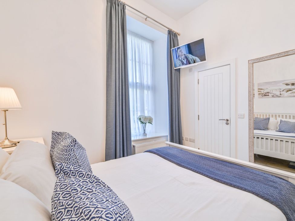 A bedroom with a bed, television, and a door at Number 2 Ellington Court Apartment in Torquay