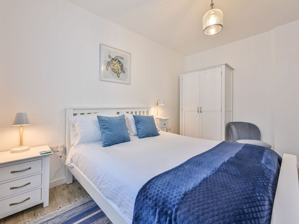 A bedroom featuring a bed with pillows and a nightstand at Number 2 Ellington Court Apartment in Torquay