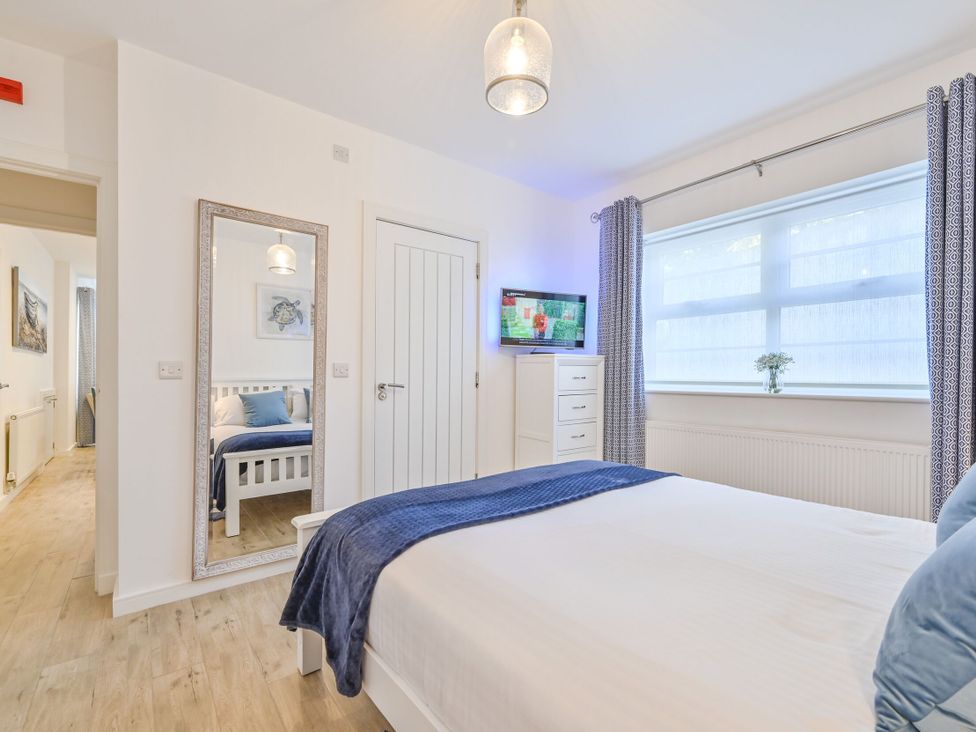 A bedroom with a bed and mirror at Number 2 Ellington Court Apartment Torquay