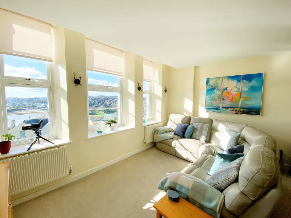 A living room with a sofa, coffee table, and telescope at Sea View Apartment, Ellington Court in Torquay