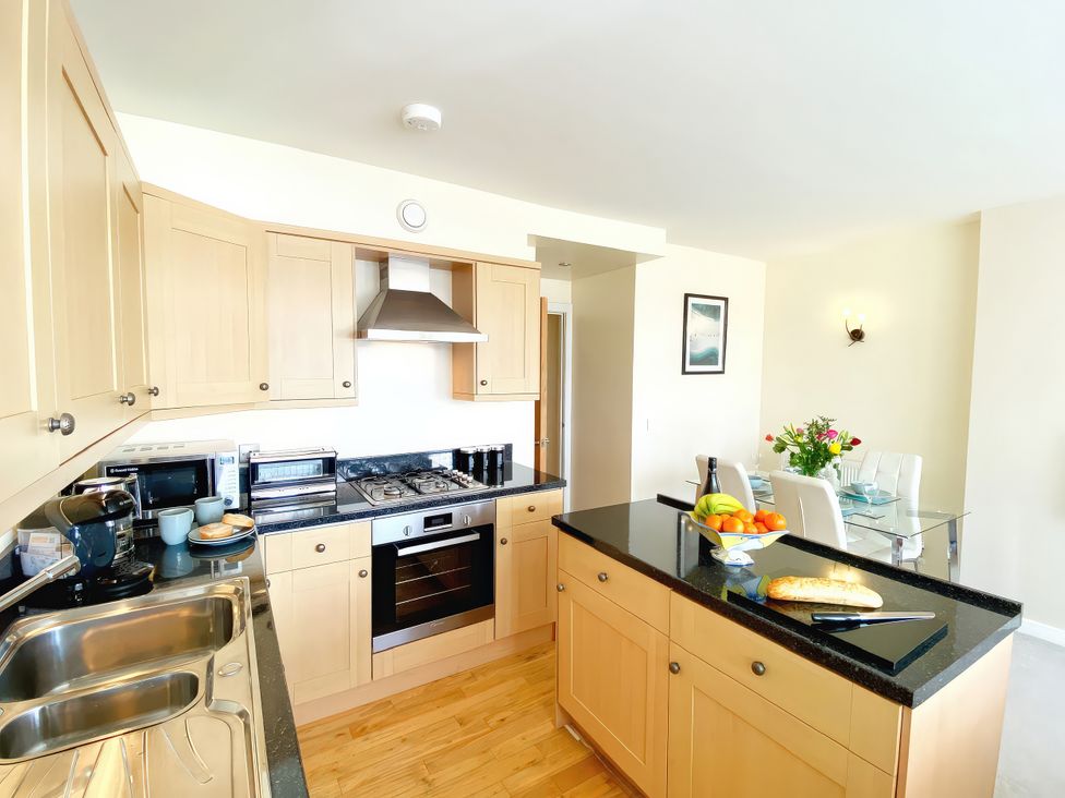A kitchen with cabinets, a sink, an oven, and a dining table at Sea View Apartment, Ellington Court in Torquay