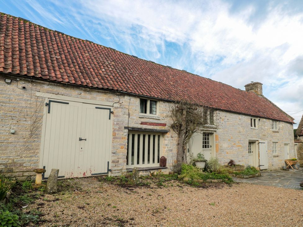 An exterior view of a stone building with a gravel pathway at The Farmhouse in Langport