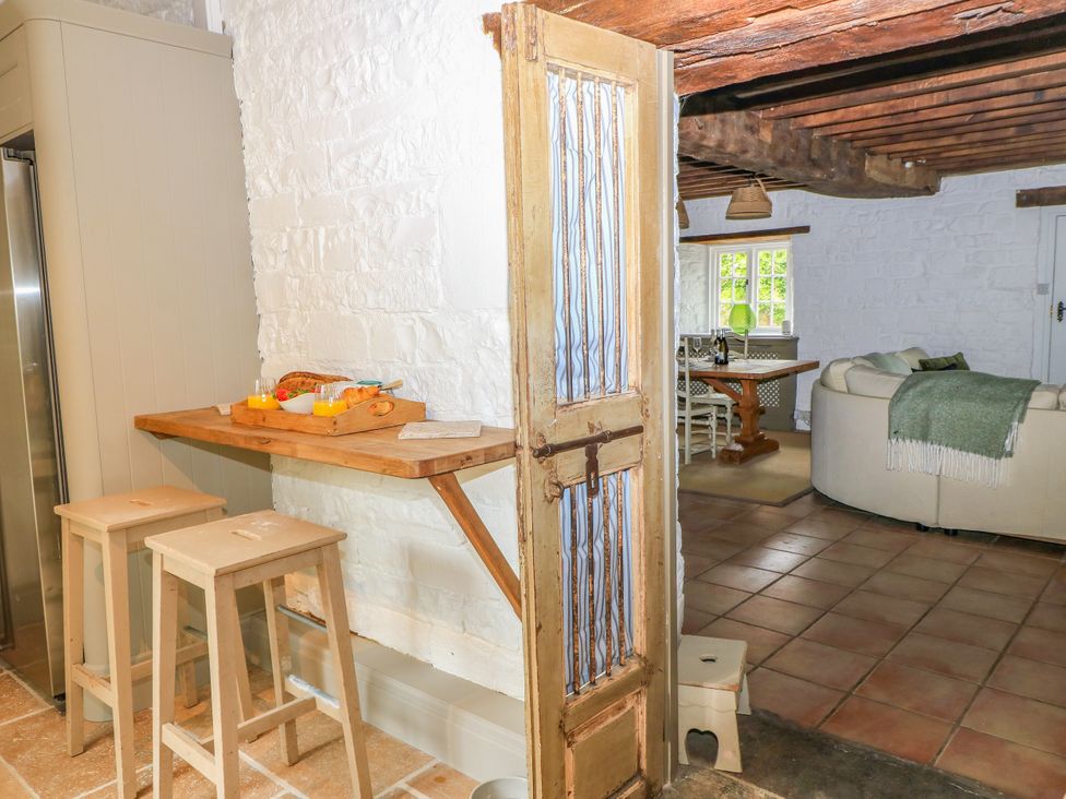A kitchen with a bar table and stools at The Farmhouse in Langport