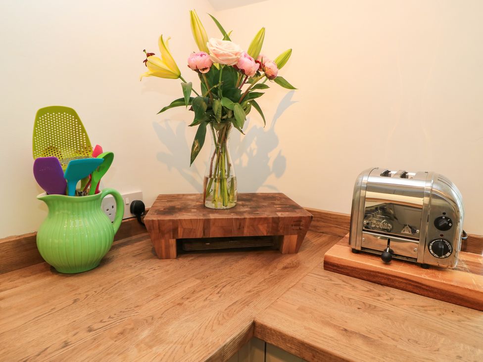 A kitchen with a flower arrangement and a toaster on a countertop at The Farmhouse in Langport