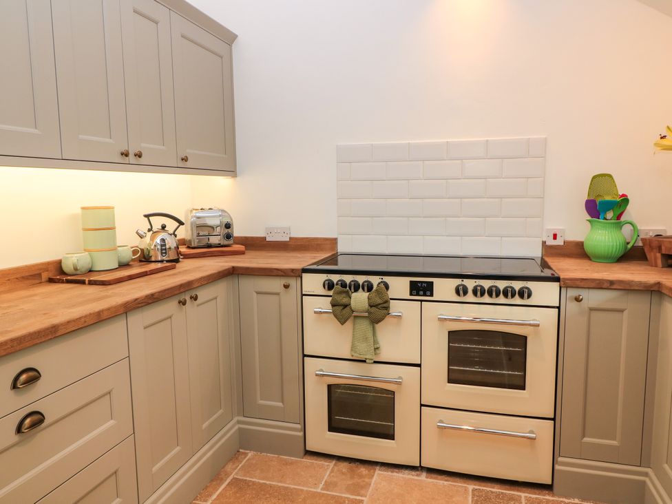 A kitchen with cabinets, countertop, stovetop, kettle, toaster at The Farmhouse in Langport