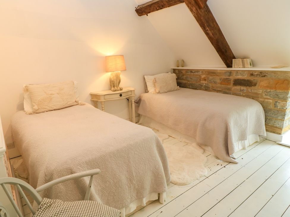 A bedroom with two beds and a lamp on a side table at The Farmhouse in Langport