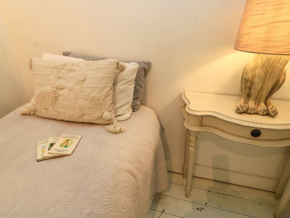 A bedroom with a bed, lamp, books, and a nightstand at The Farmhouse in Langport