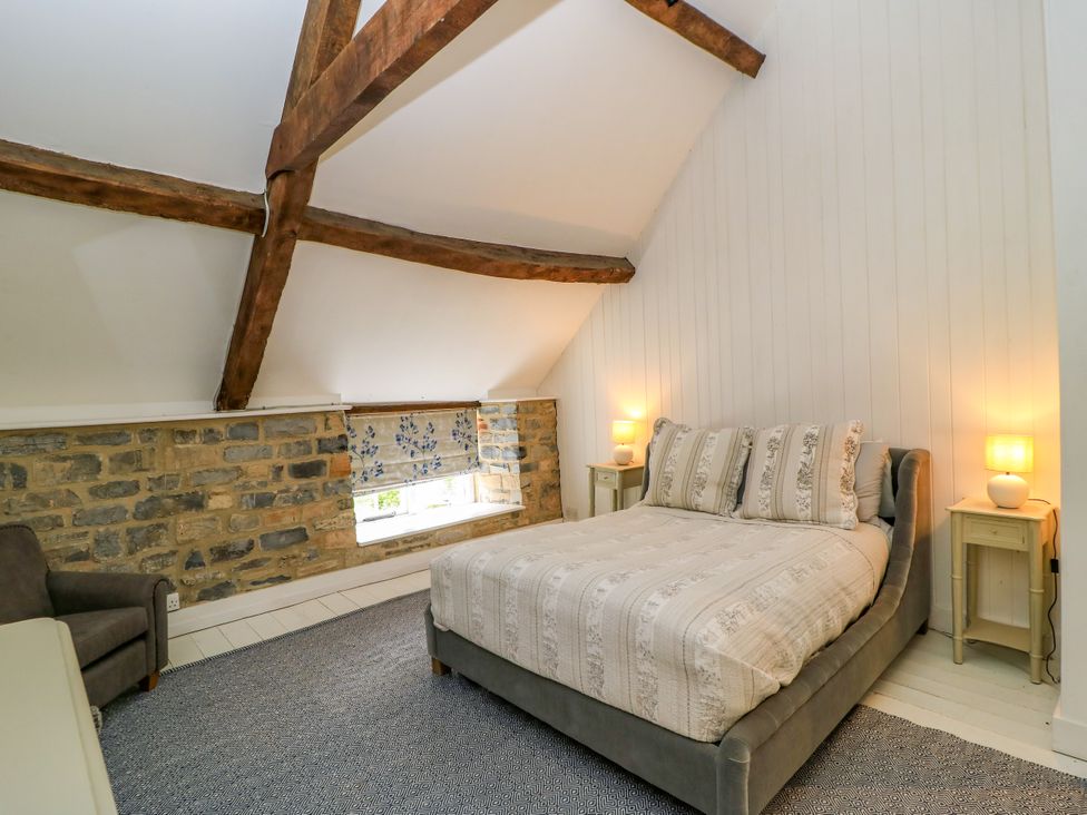 A bedroom with a bed and a chair at The Farmhouse in Langport