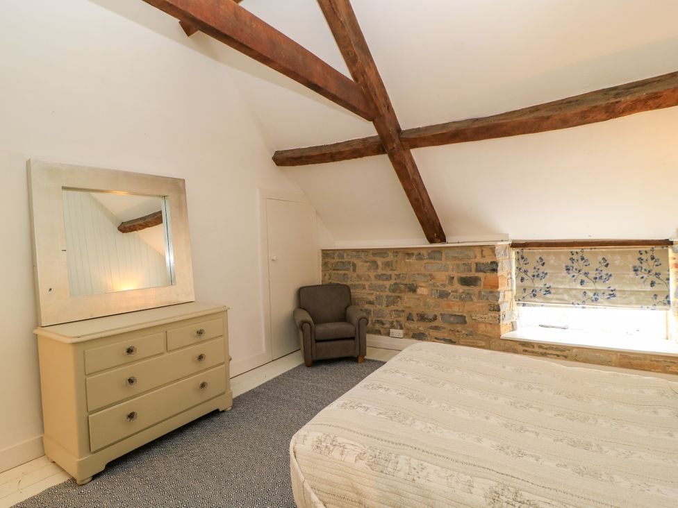 A bedroom with a bed, dressing table, and chair at The Farmhouse in Langport