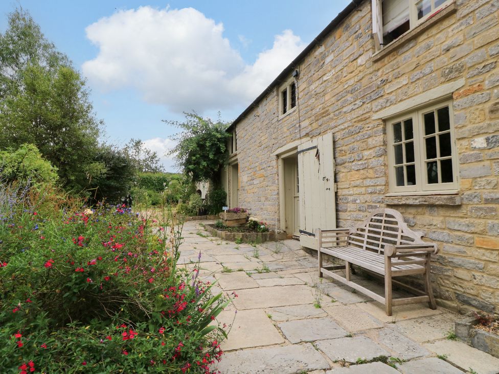 An outdoor view with a bench and flower bed at The Farmhouse in Langport