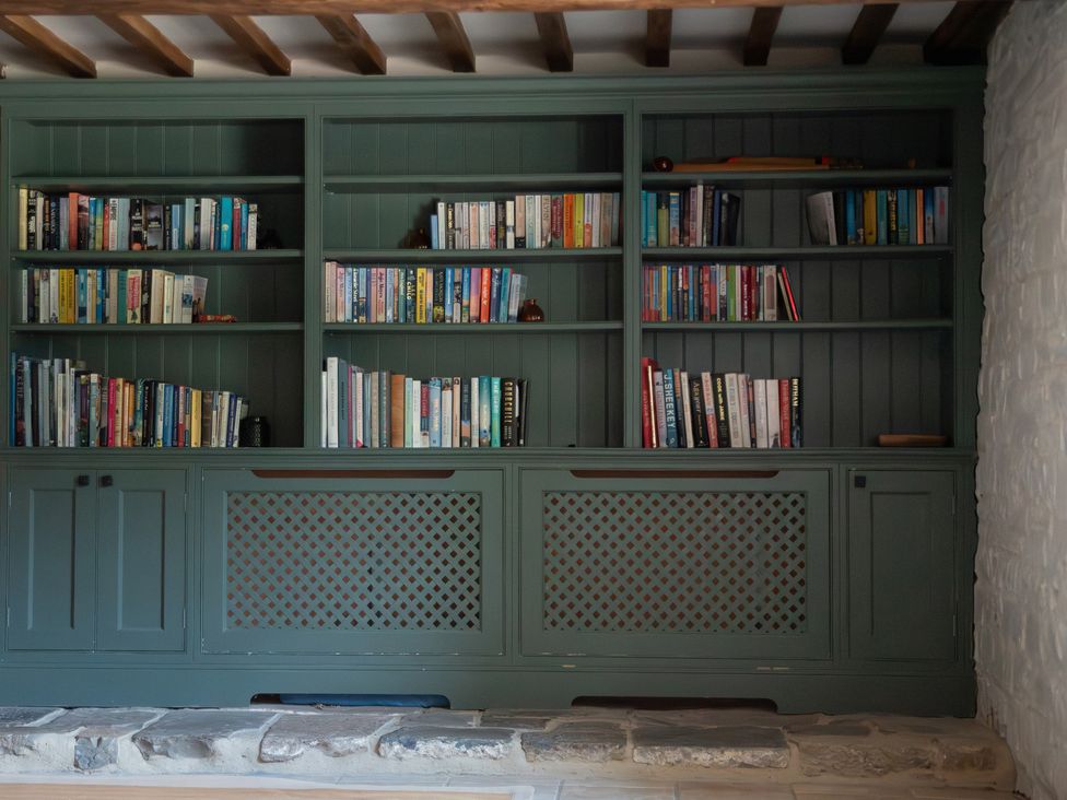 A bookshelf with various books and decorative objects at The Farmhouse in Langport
