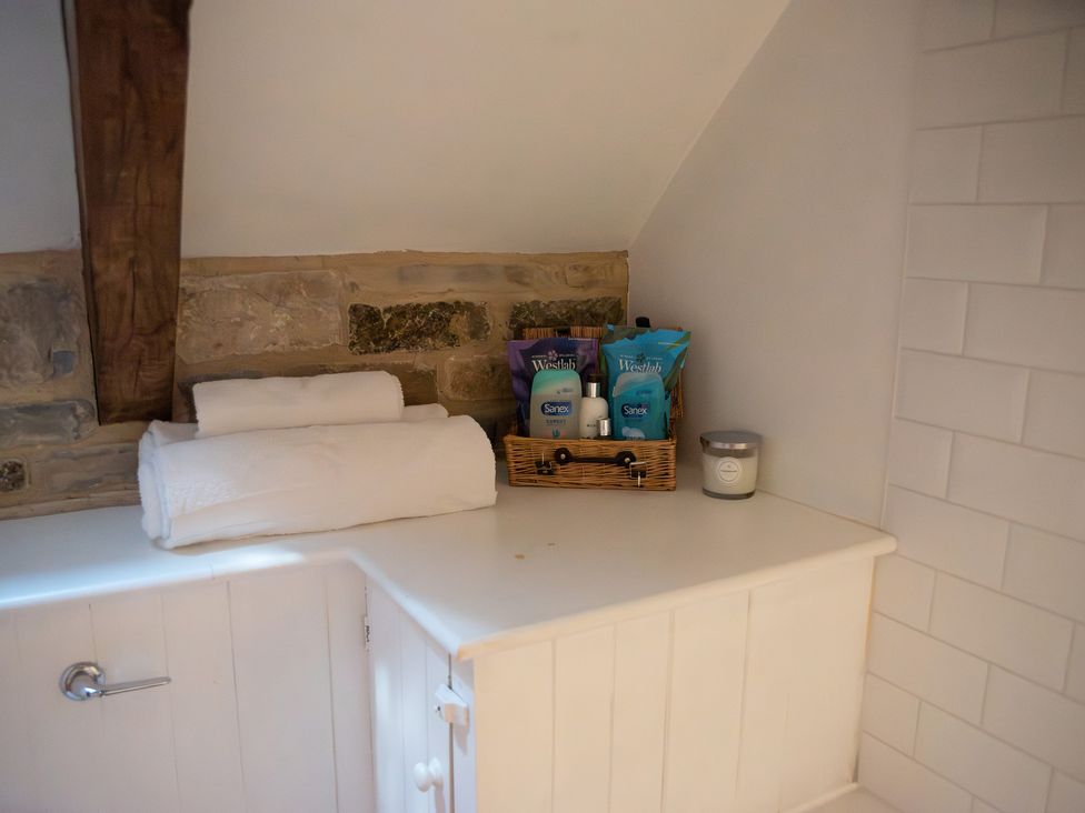 A bathroom counter with towels and toiletries at The Farmhouse in Langport