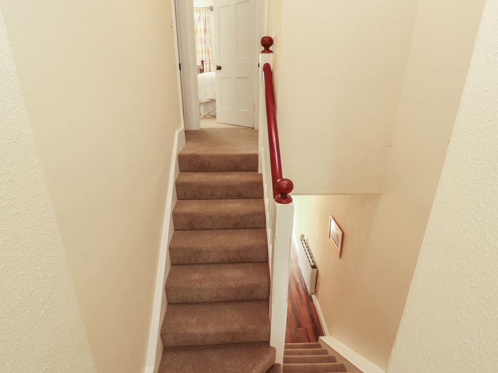A staircase with a handrail and a door at East View Ravenstonedale near Kirkby Stephen