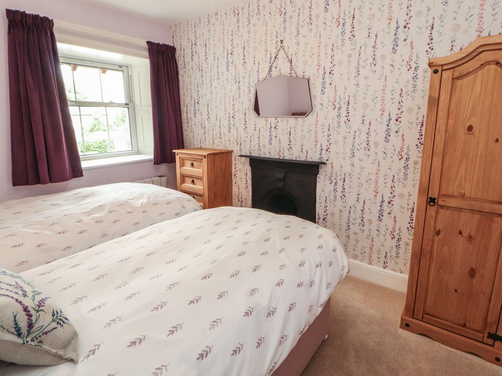 A bedroom with two beds and a window at East View in Ravenstonedale near Kirkby Stephen