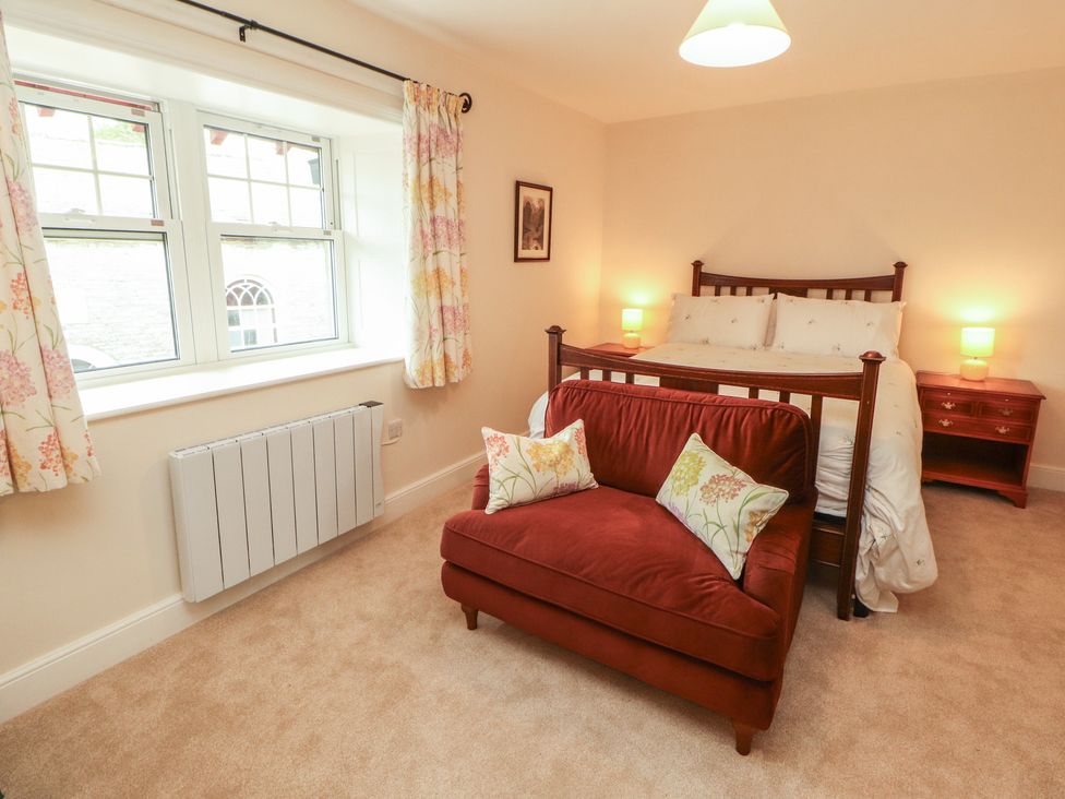A bedroom with a bed and armchair at East View in Ravenstonedale near Kirkby Stephen
