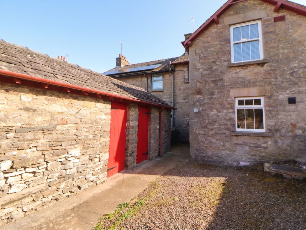 An outdoor area with stone walls and red doors at East View in Ravenstonedale near Kirkby Stephen