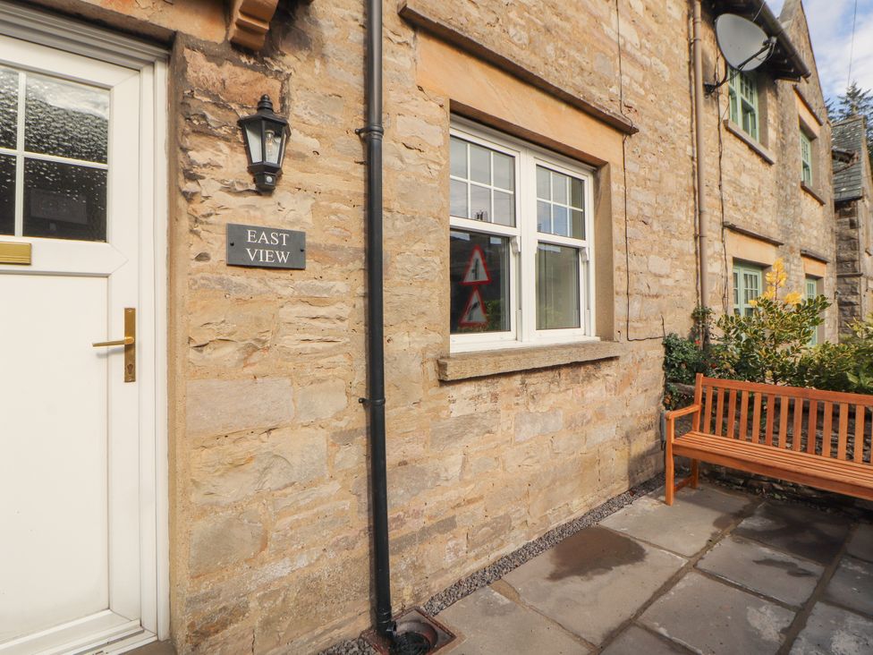 An outdoor entrance with a door, window, and bench at East View in Ravenstonedale near Kirkby Stephen
