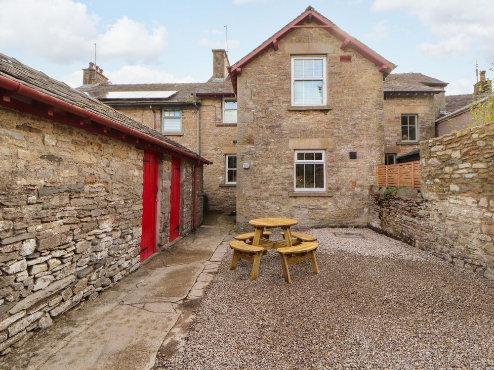An outdoor area with a wooden table and stone walls at East View Ravenstonedale near Kirkby Stephen