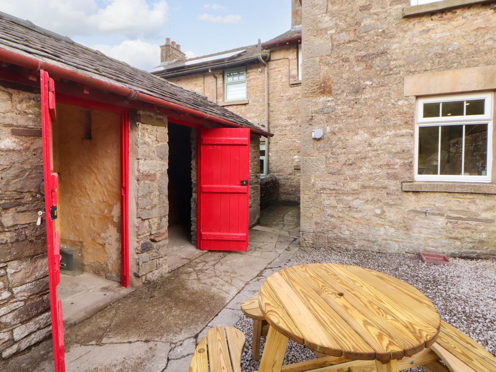 An outdoor area with a red door and wooden table at East View Ravenstonedale near Kirkby Stephen