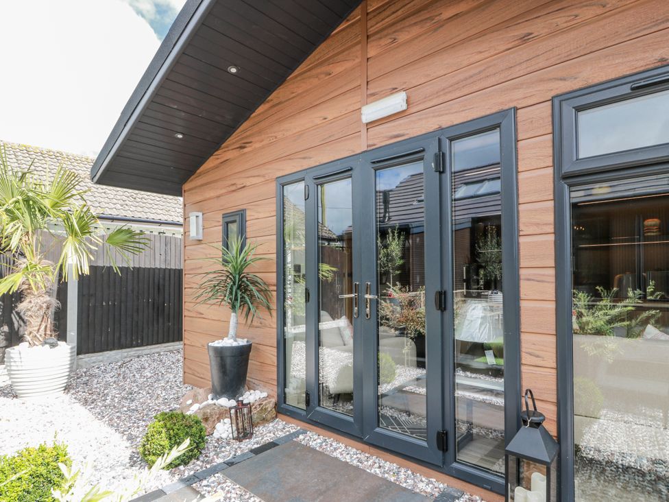 An outdoor area with double doors and plants at Cabin At The Brig Annan