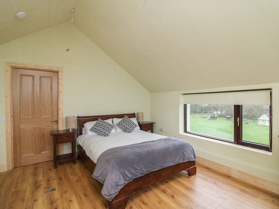 A bedroom with a bed and side table at The Rookery in Rosslare Harbour, County Wexford