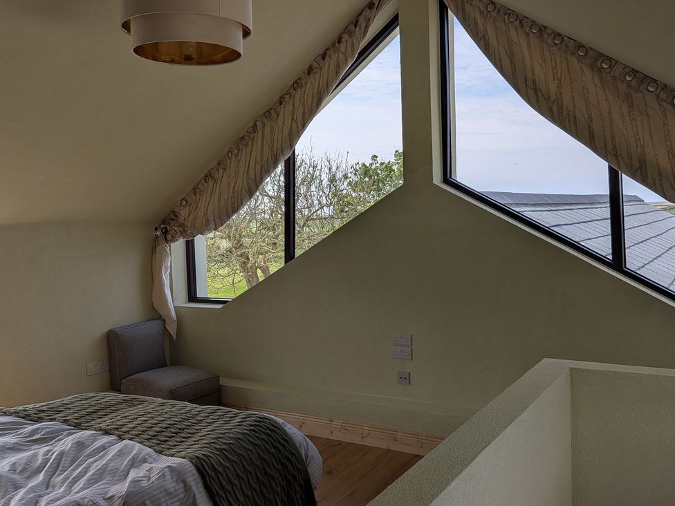 A bedroom with a bed and windows at The Rookery in Rosslare Harbour, County Wexford