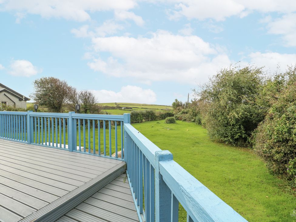 A deck overlooking a grassy area and bushes at Harbour Lights in Holyhead