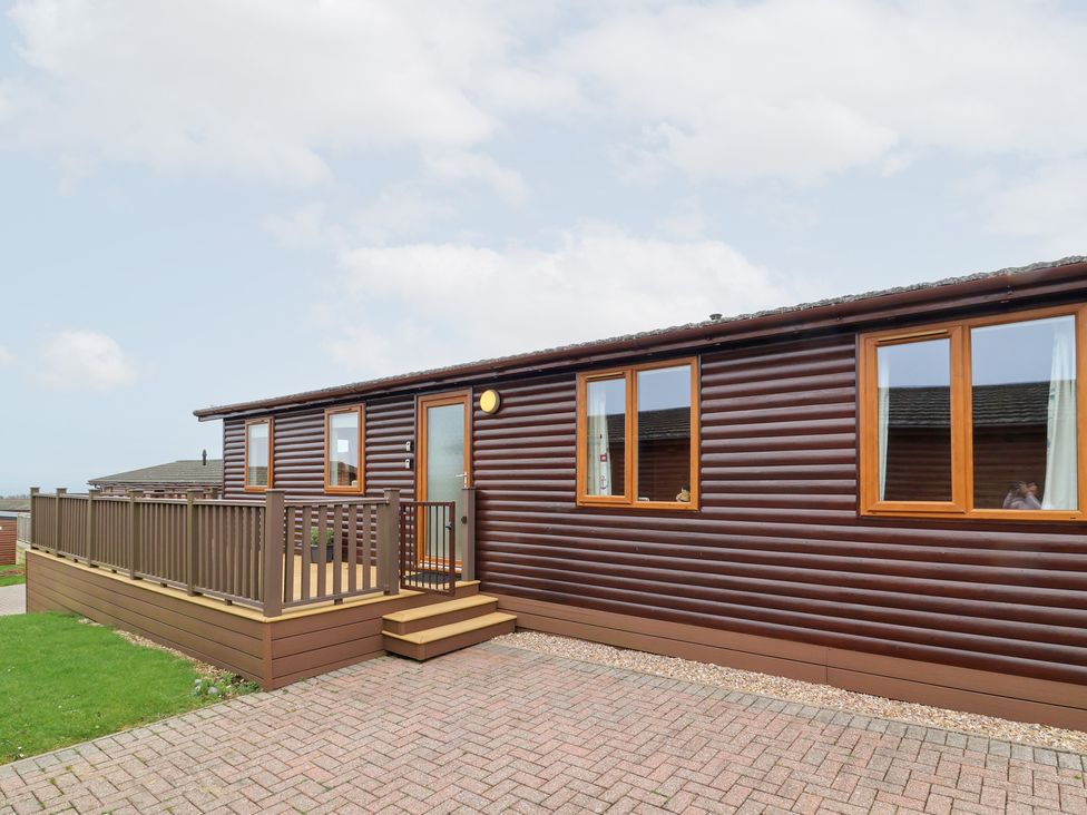 A wooden cabin with a deck and windows at Ocean Terrace 28 Ilfracombe