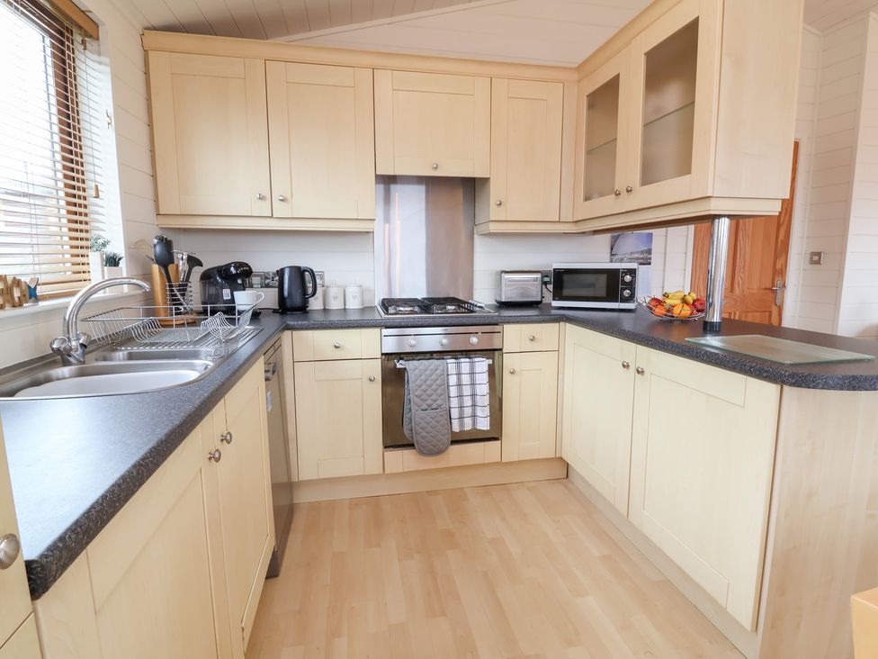 A kitchen with a sink, stove, microwave, and kettle at Ocean Terrace 28 Ilfracombe