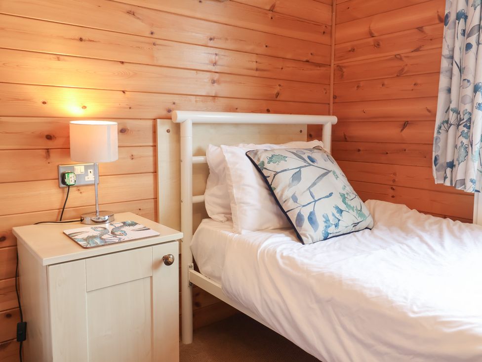 A bedroom with a bed, nightstand and lamp at Ocean Terrace 28 in Ilfracombe