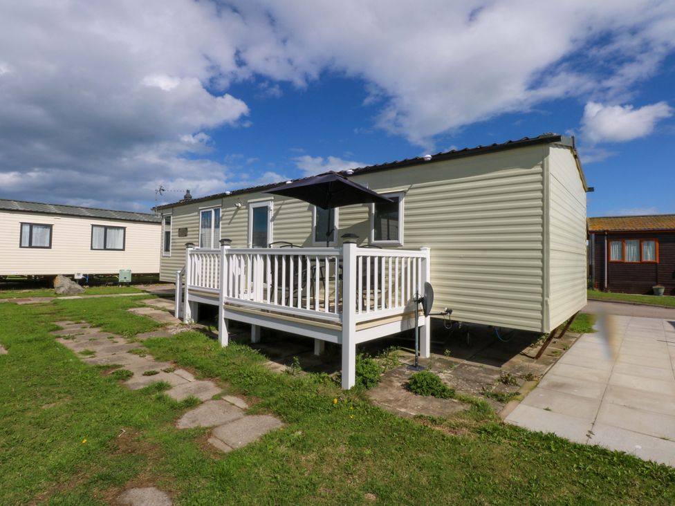 A static caravan with a deck and patio at Hideaway Lodge in Abergele
